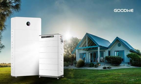 GoodWe Lynx Home battery modules stacked beside a hybrid inverter, with a coastal NSW home behind